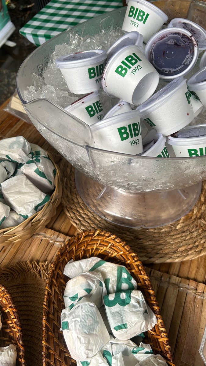 Copos Bibi 1993 servidos no gelo ao lado de sanduíches embalados